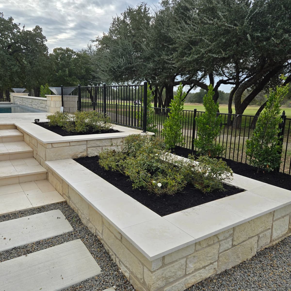 Raised limestone planting beds refreshed with dark mulch